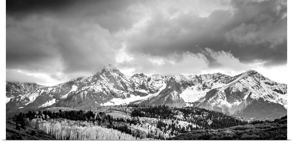 Black and white landscape photograph of snowy mountains under a cloudy sky.