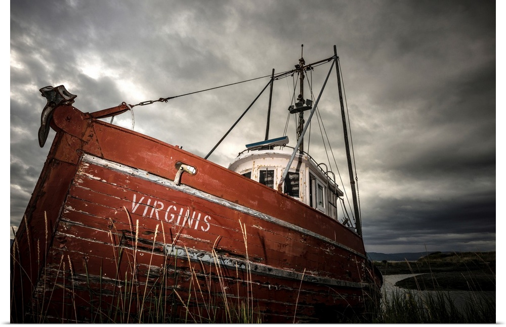 Photograph of an old red boat called "Virginis" pulled up on the shore on a dark overcast day.