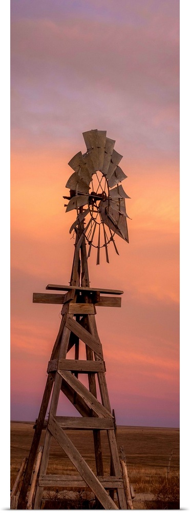 Tall photograph of a wooden windmill at sunset.