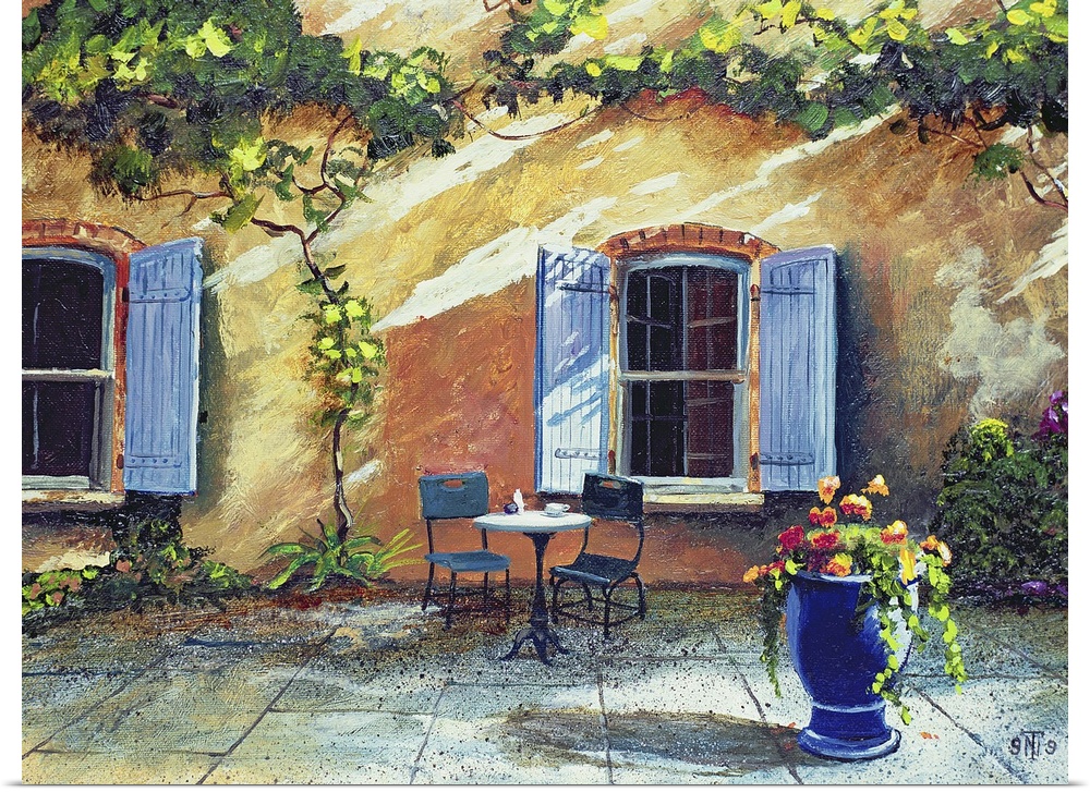 Painted outdoor patio of two chairs and a table in front of a vine covered rustic wall with large blue shutter windows.
