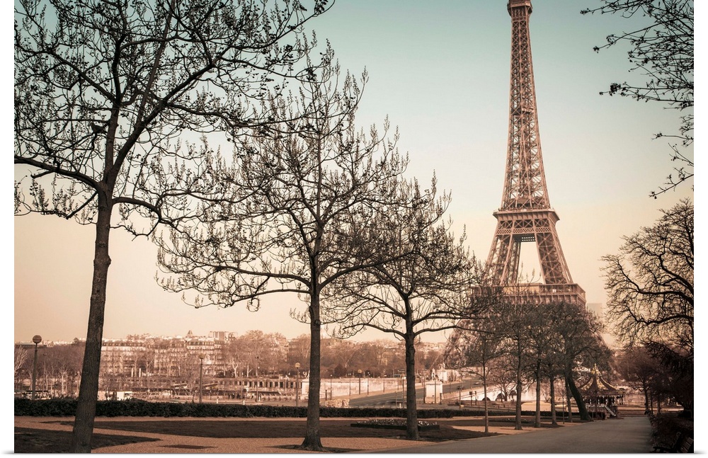 A muted colored photograph of the Eiffel Tower, viewed from a park sidewalk, in Paris, France.