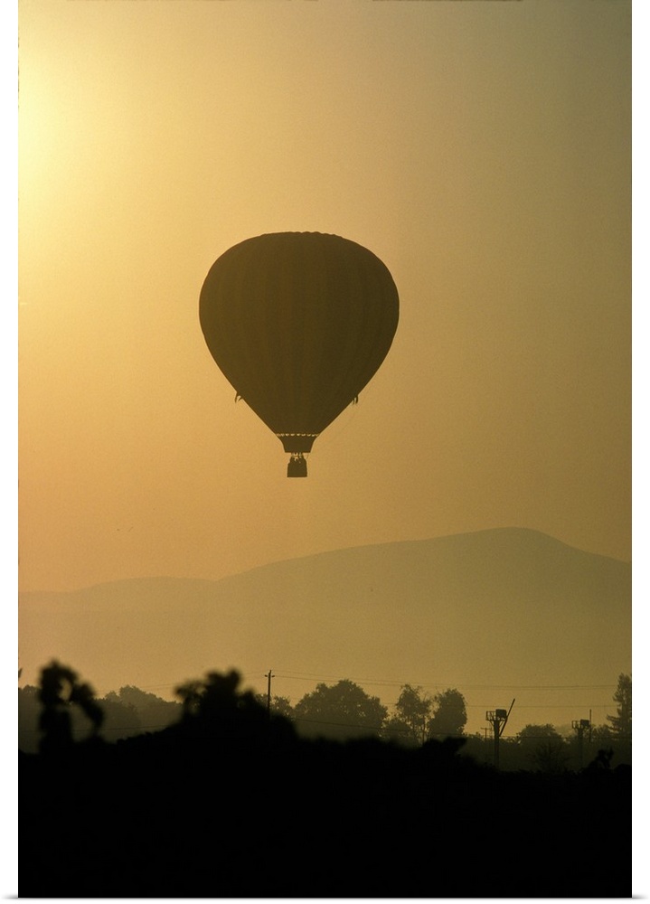 Hot air balloon lifting over Napa valley at sunrise.