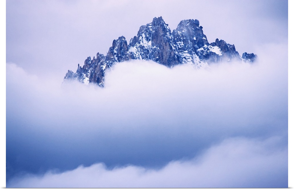 USA, Idaho, Sawtooth Range. Mountain top peaks through the heavy clouds.