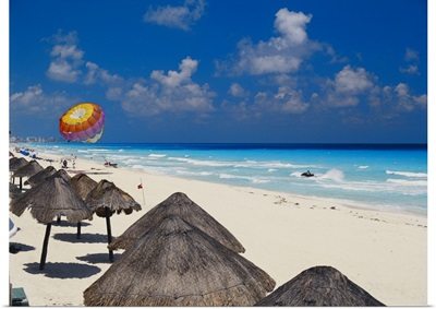 Mexico, Cancun, sunshades along beach with parachute in background