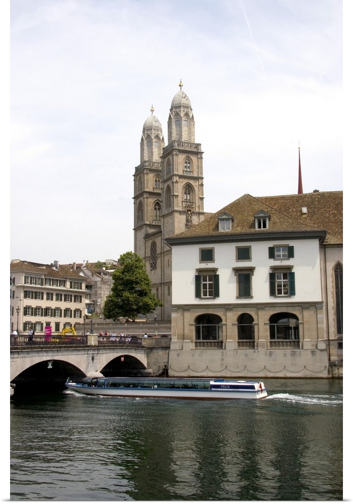 Tour boat passes beneath Munster Bridge crossing the Limmat River in Zurich, Switzerland with towers of Grossmunster churc...