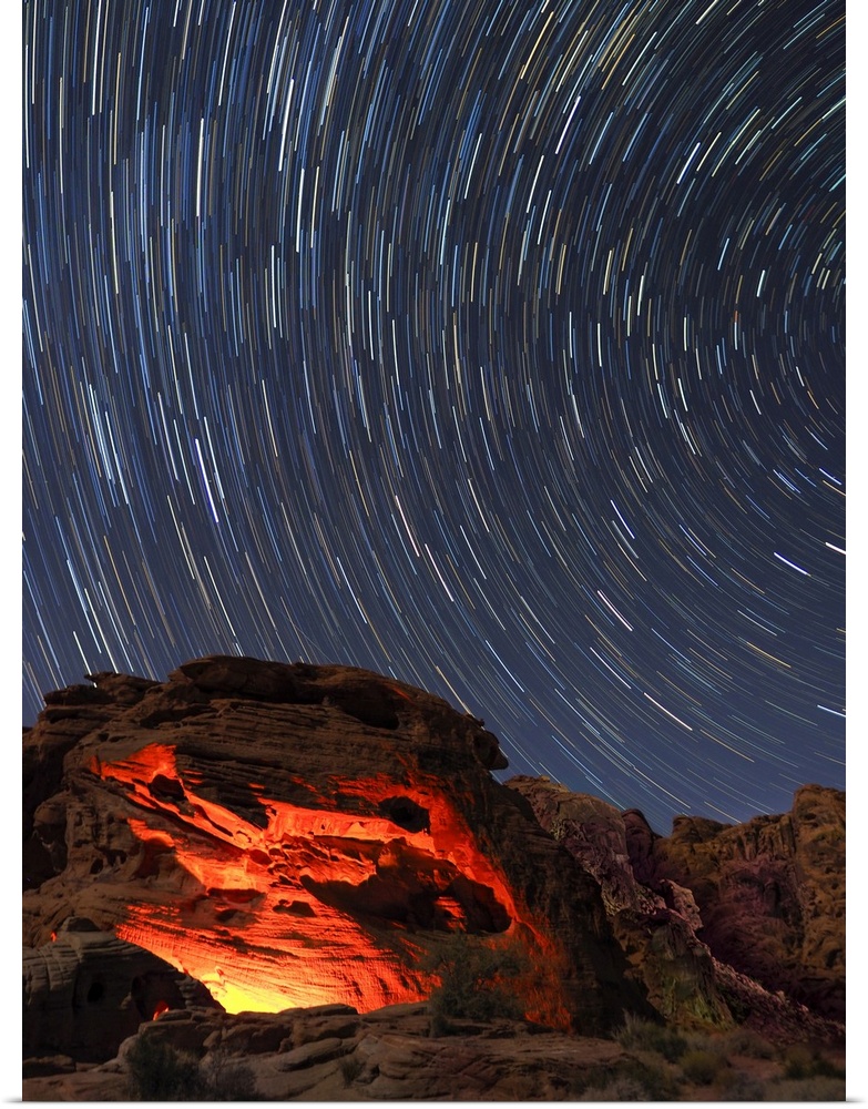 Usa, Nevada. Valley of Fire State Park, star trails and campfire glowing in sandstone rocks.