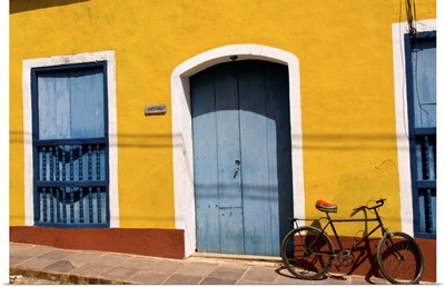 Old yellow building in colonial town of Trinidad Cuba with bike against wall