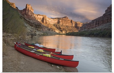 Utah, Canyonlands National Park, three red canoes rest on bank of Green River