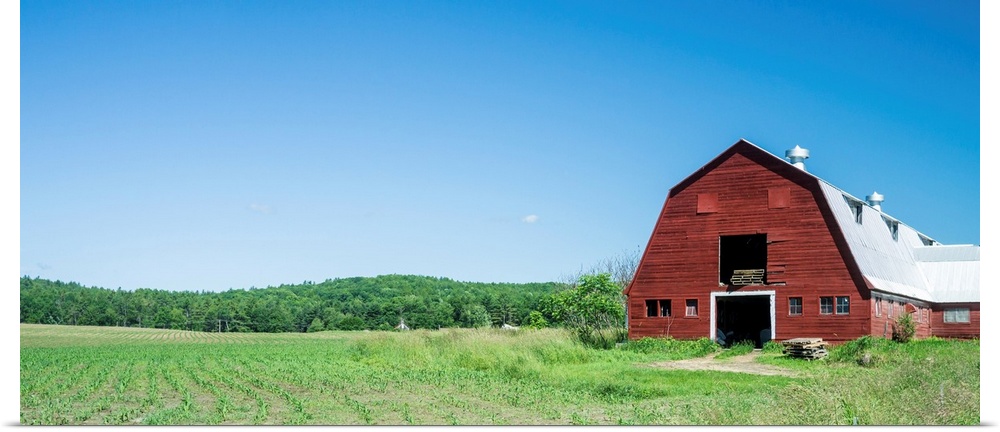 A red barn, green fields, and blue sky of a classic Vermont family farm.