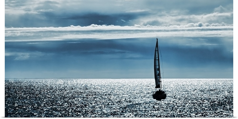 Silhouettes of a yacht sailing alone in the ocean to the horizon.