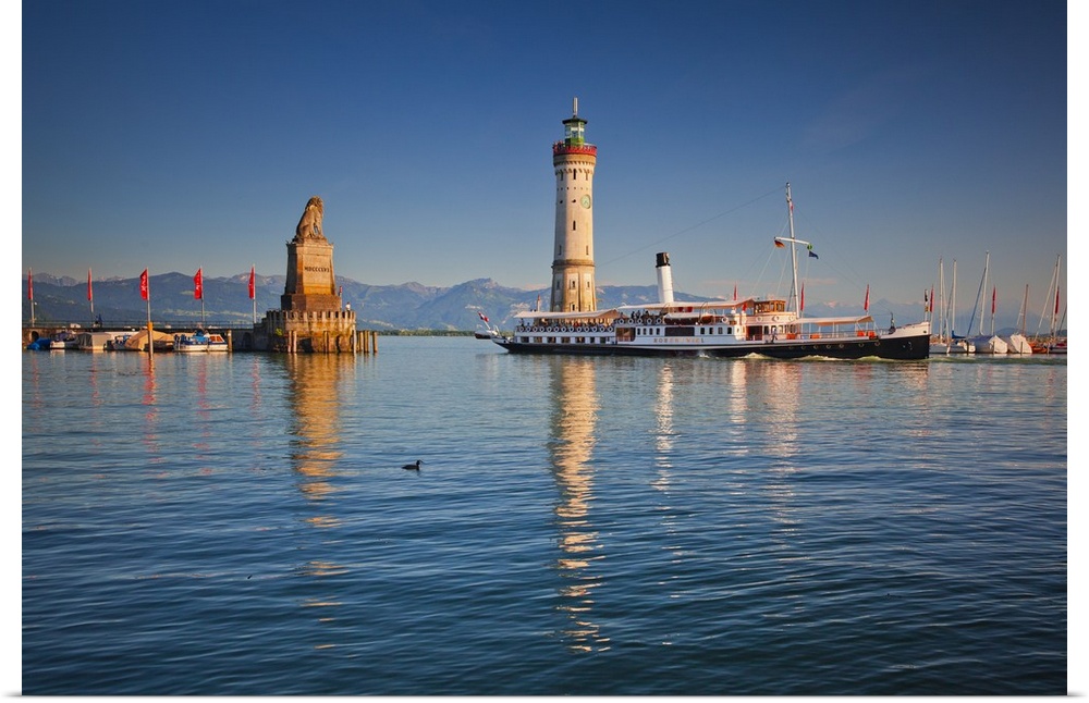 Germany, Bavaria, Lake Constance, Swabia, Schwaben, Lindau, Lighthouse and a passenger ship at the harbor entrance at sunset.