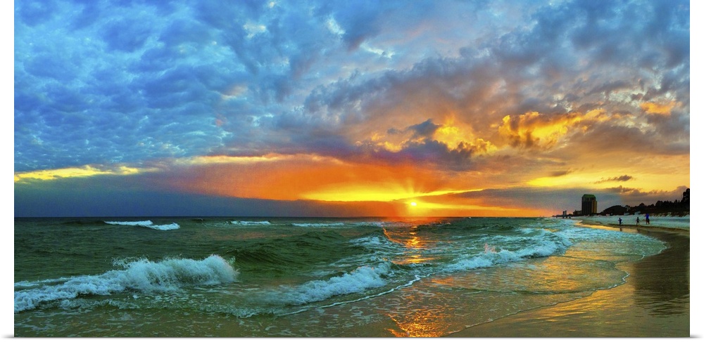 Waves flow over the shore in a soft white foam. Dark yellow, blue, and orange skyscape. Landscape taken on Navarre Beach, ...