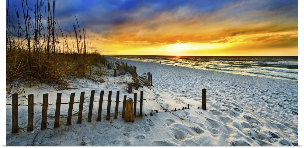 White sandy shore in a panoramic landscape with a burning red sunset sky. Landscape taken on Navarre Beach, Florida.