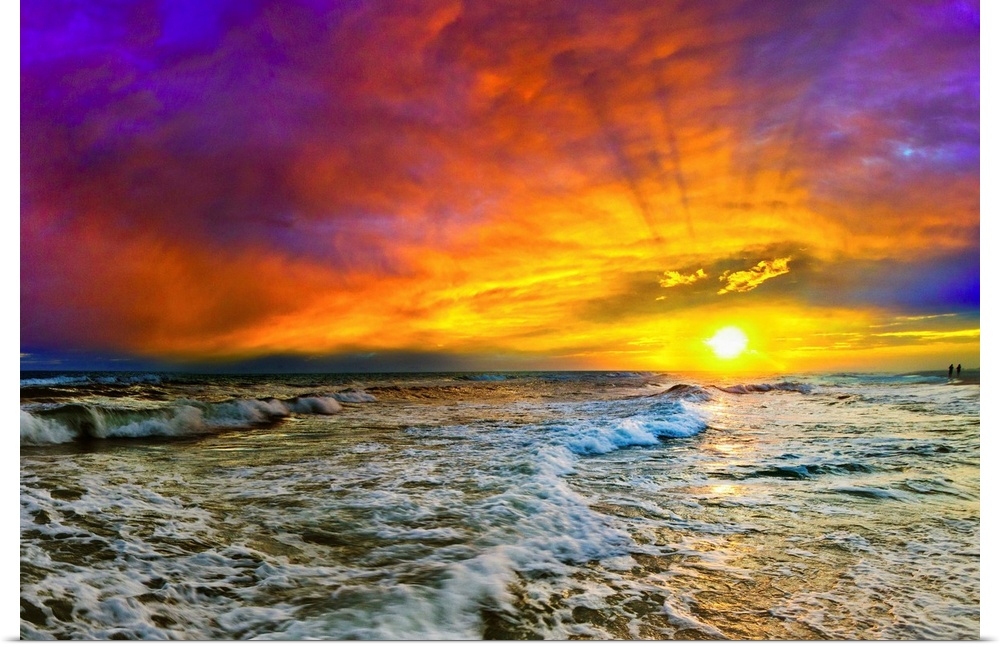 A beautiful purple, blue, and red sunset with shooting sun rays over the ocean. The yellow sun casts a sun trail and the sea.