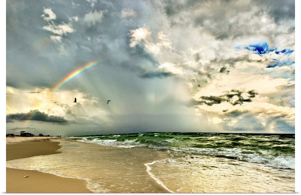 A rainbow appears through the clouds over an emerald green sea and a Florida beach. Landscape taken near Pensacola Beach, ...