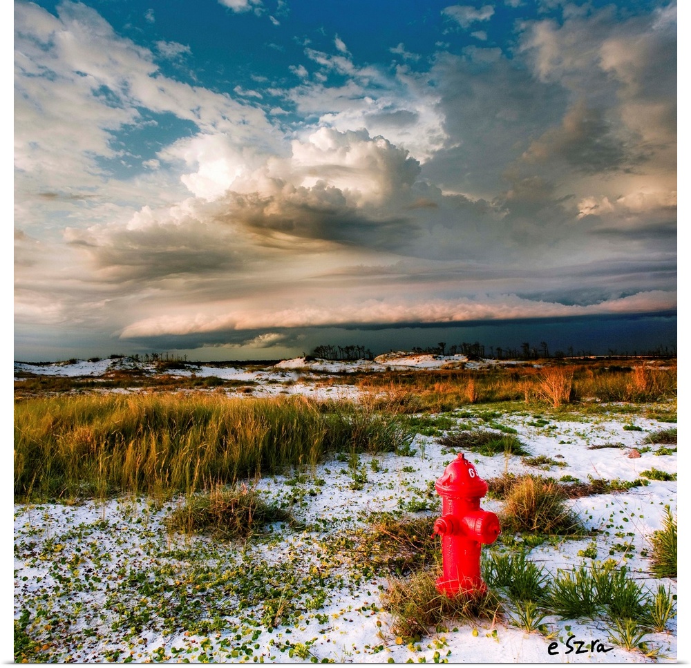 A red hydrant a midst a desert landscape with storm clouds overhead.