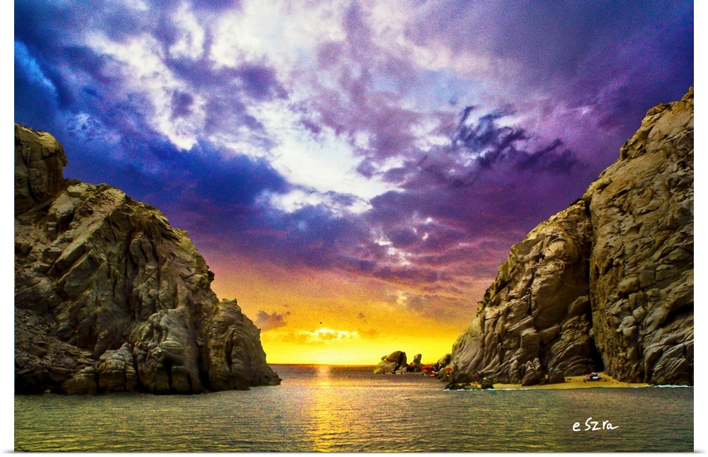 A sunset through a rocky sea passage during calm waters.