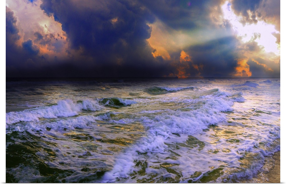 Sun rays break through dark blue clouds on a stormy night over a dark ocean and waves.