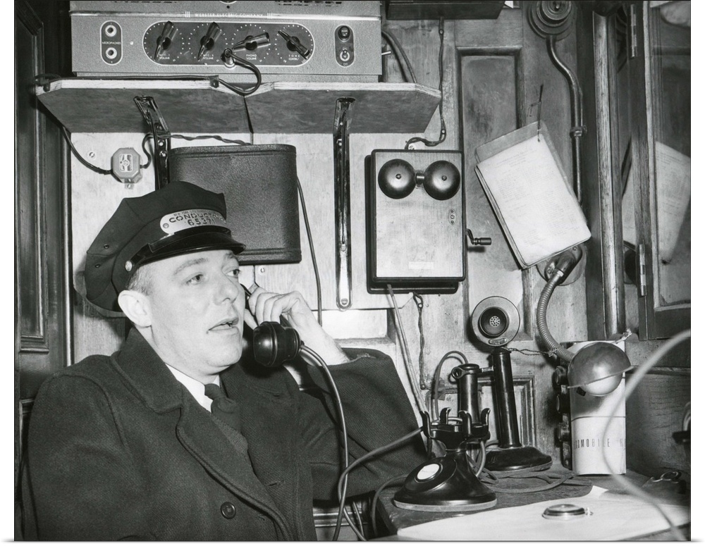 Railroad conductor uses an on board telephone to communicate with other parts of the train. c. 1930's