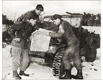 Elvis Presley and other soldiers read a map on maneuvers in Germany