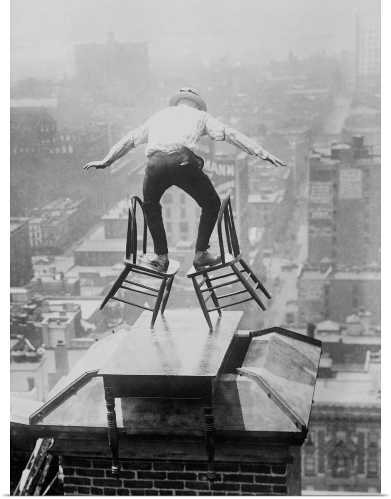 Human Fly' John 'Jammie' Reynolds balances precariously on two tilted chairs. The dare-devil is on the roof edge of a tall...