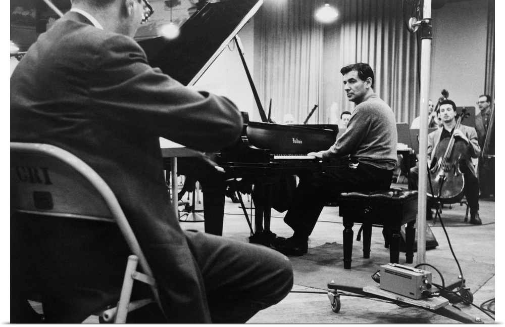 Leonard Bernstein, playing piano, amidst other musicians during a rehearsal in 1958.