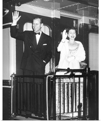Queen Elizabeth II and Prince Philip wave from the back of a train at Union Station