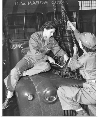 Women Marines lower a reconditioned engine back in place in a Marine Corps bus