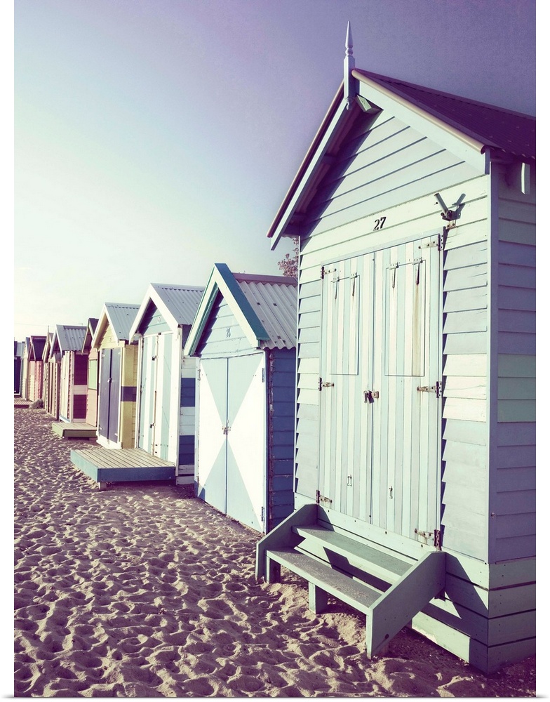 Slightly faded photograph of a row of colorful beach cottages right on the sand.