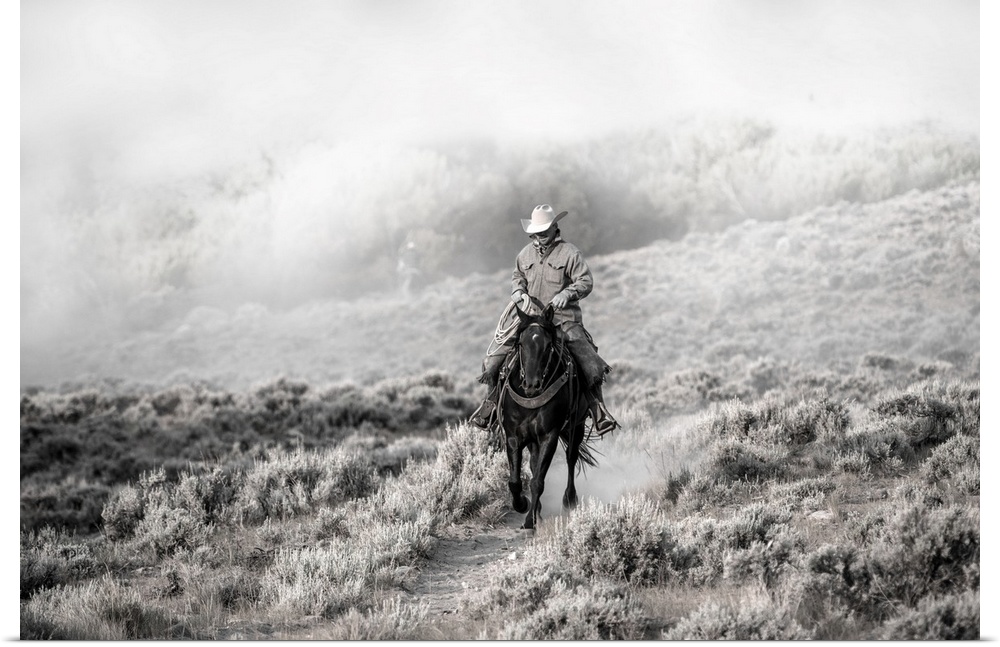 Lone wrangler riding back from herding horses.