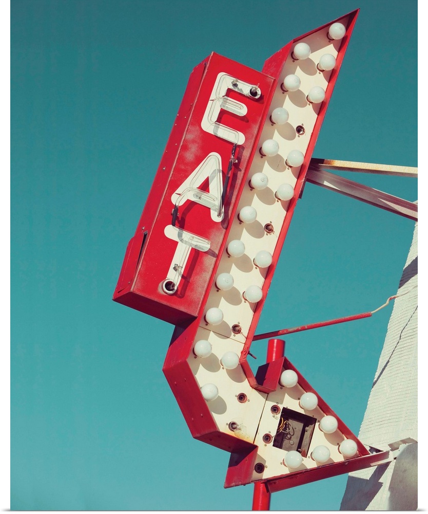 Photograph of a vintage red and white light up 'EAT' sign with an arrow on a blue sky background.