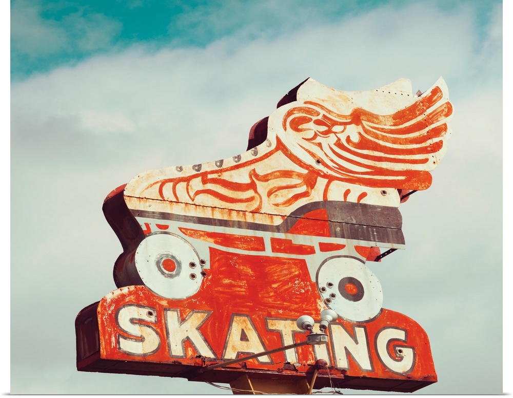 Photograph of a vintage orange roller skating sign on a cloudy sky background.