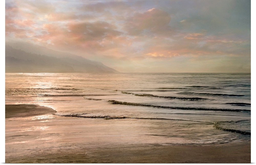 A photograph of small waves coming to shore with mountains in the background and a pink sunset.