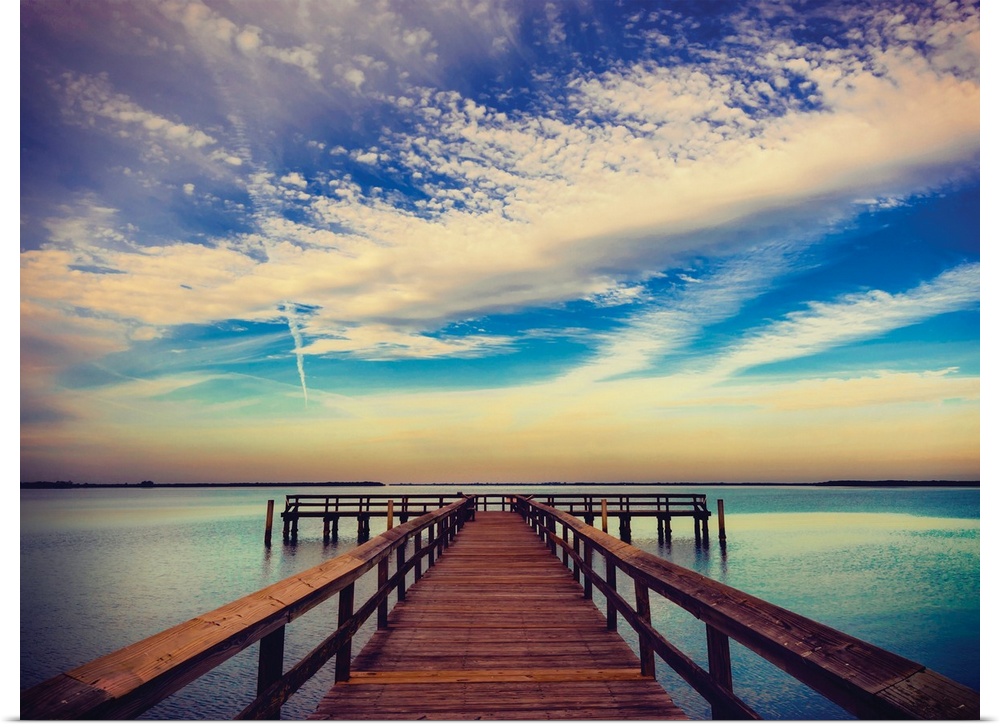 Photograph of a pier at sunrise with beautiful clouds.