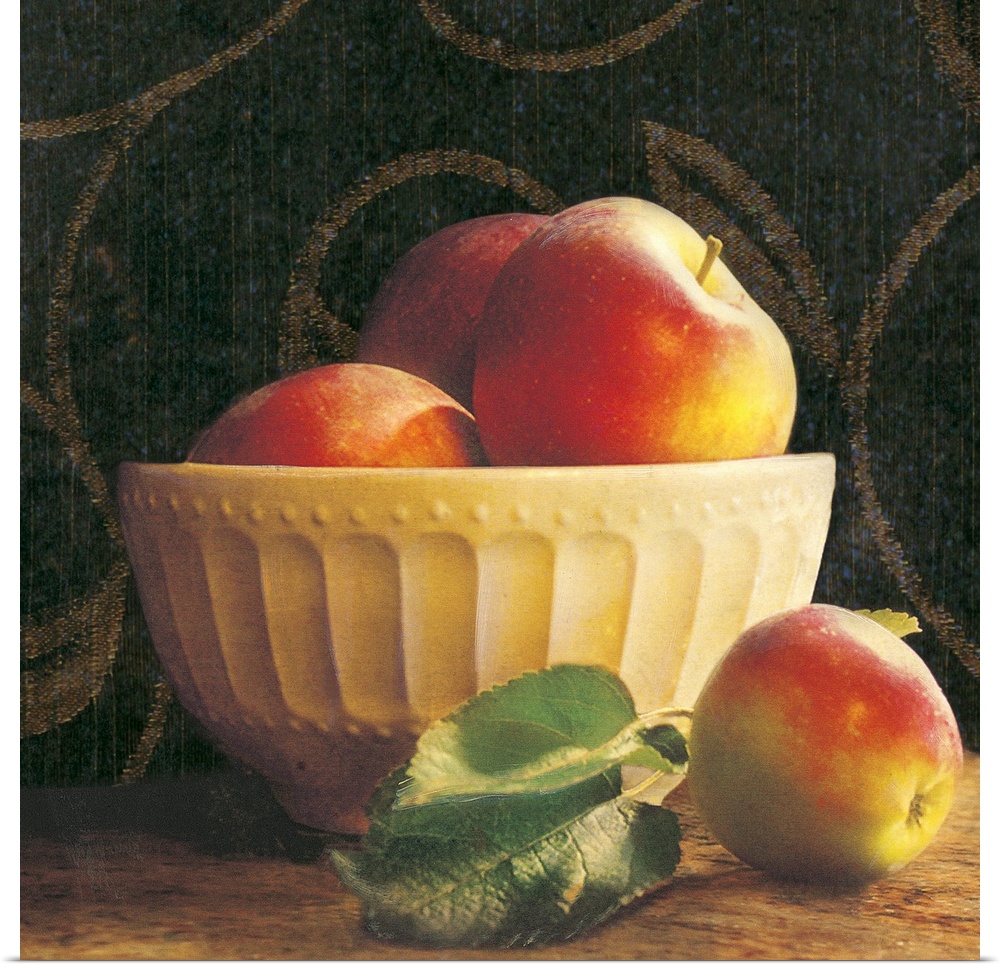Giant photograph shows a group of three apples sticking out the top of an ornamental bowl on a table, while a lone apple a...