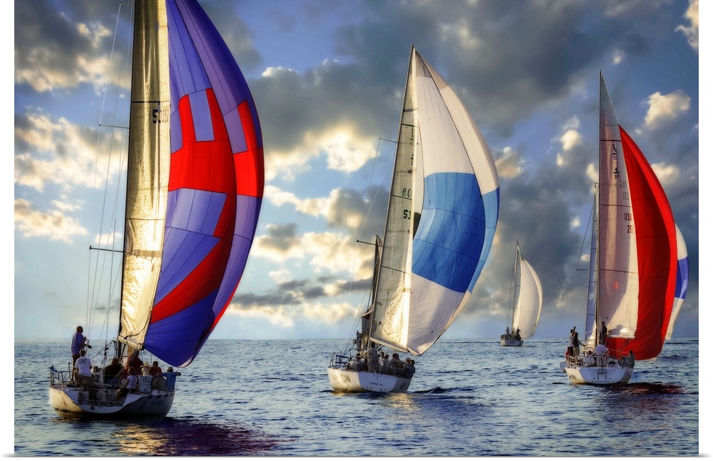 A regatta of colorful sailboats with a cloudy sky.