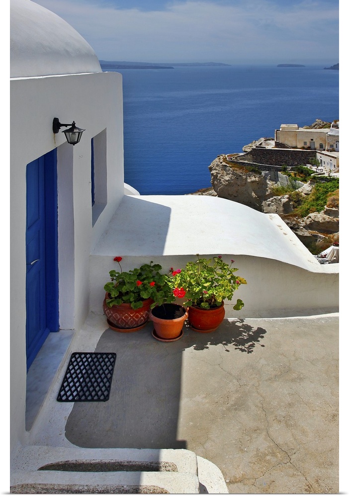 Vertical photo of home with blue door and ocean view in the village of Oia on the island of Santorini, Greece