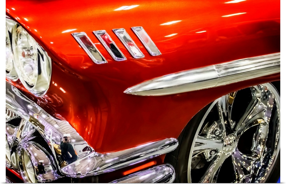 Headlight and wheel rim detail of a bright red muscle car.