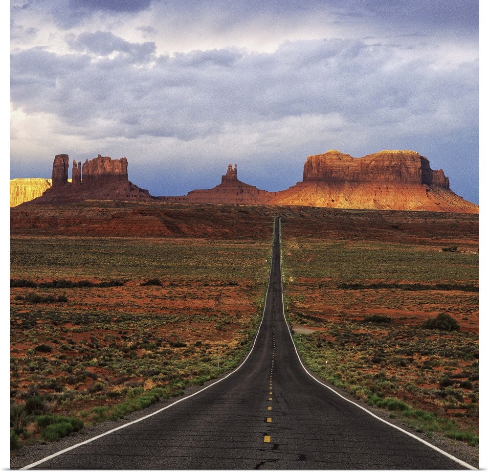 A road leading towards the tall rock formations in Monument Valley, Arizona.