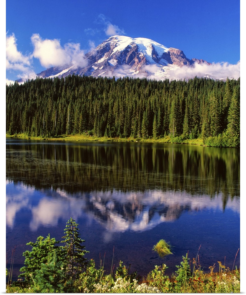 Mount Rainier surrounded by clouds seen from a lake.