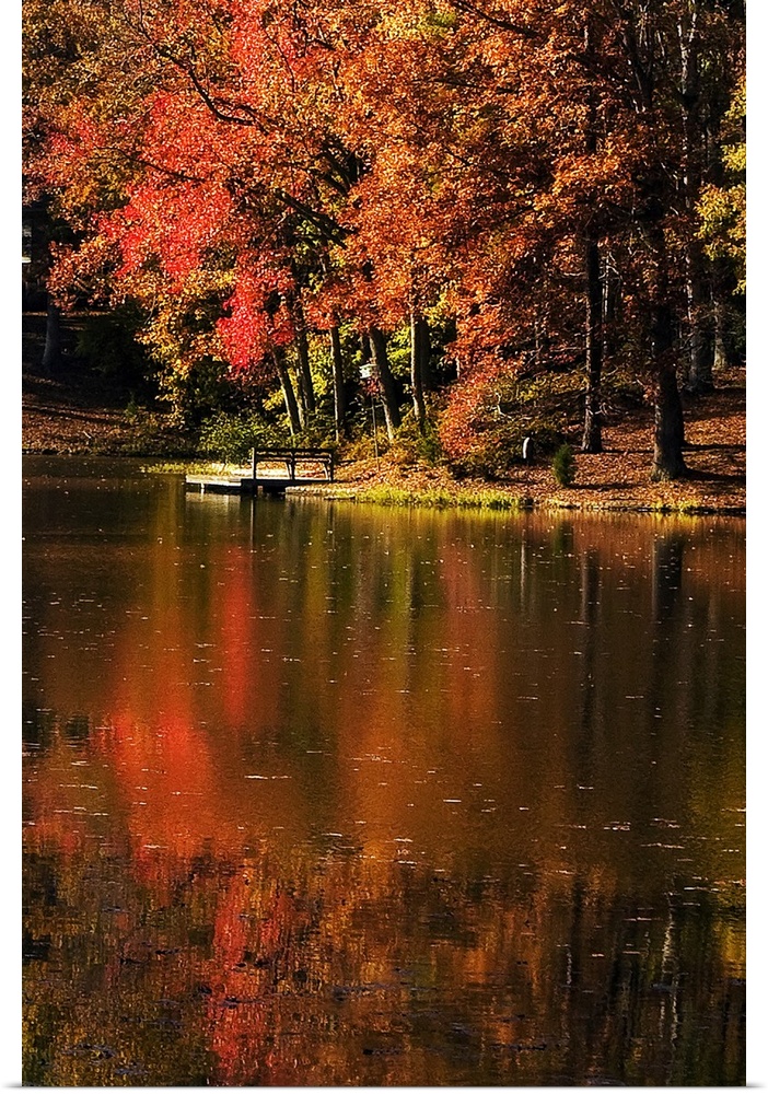 Vertical photo on canvas of a lake with a dock and fall foliage surrounding it.