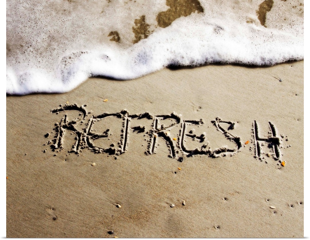 The word "Refresh" drawn in the sand near the ocean water.