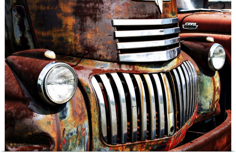 Close-up photograph of the headlights and grill of an old and rusty truck.