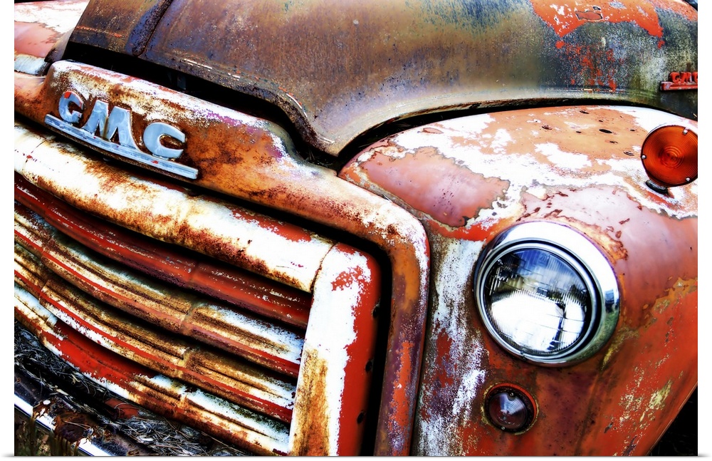 Photograph of the front of an old, rusted, orange GMC truck.