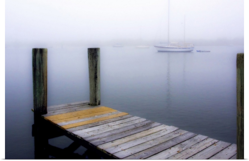 Giant, horizontal wall picture of a wooden dock leading into calm water, several boats can be seen in the foggy background.