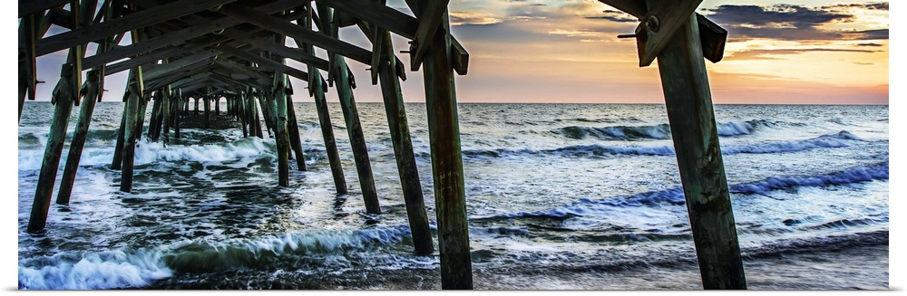 Wooden piers in the ocean silhouetted at sunset.