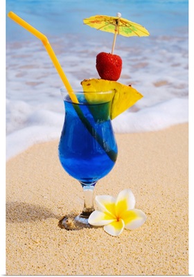 A Blue Hawaii tropical cocktail on the beach, wave washing on the sand.