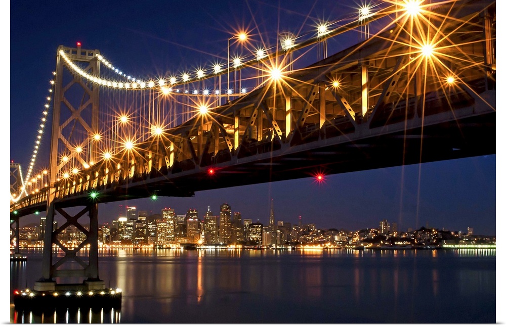 A burst of lights on the Bay Bridge and San Francisco skyline in the background.