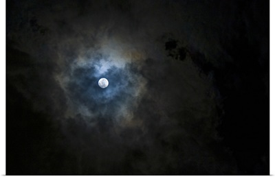 A full moon shining through a break in the clouds