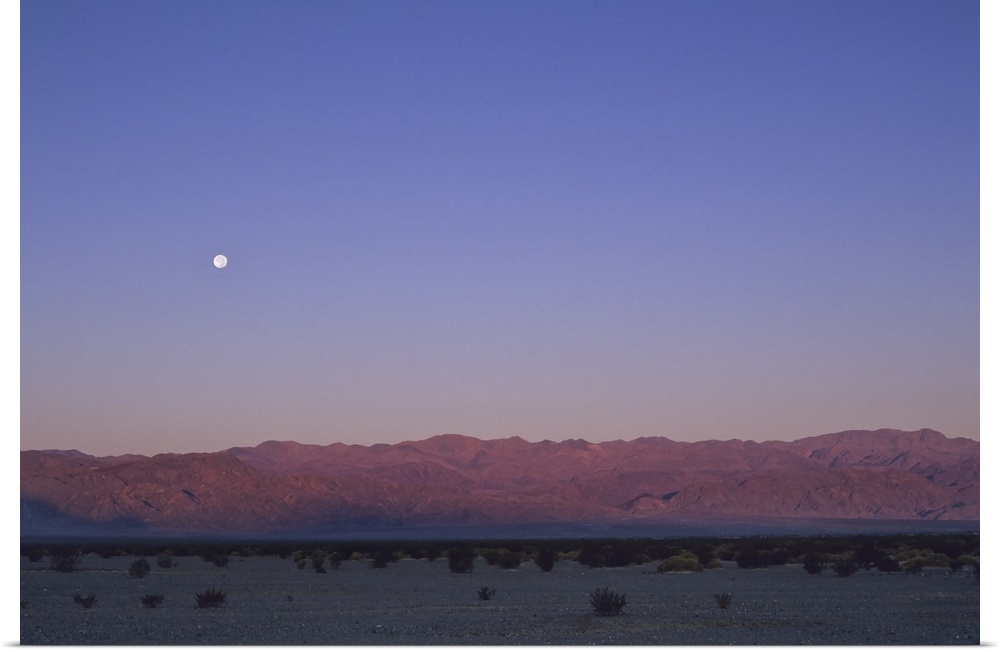 A moon above a mountain range in Death Valley National Park.